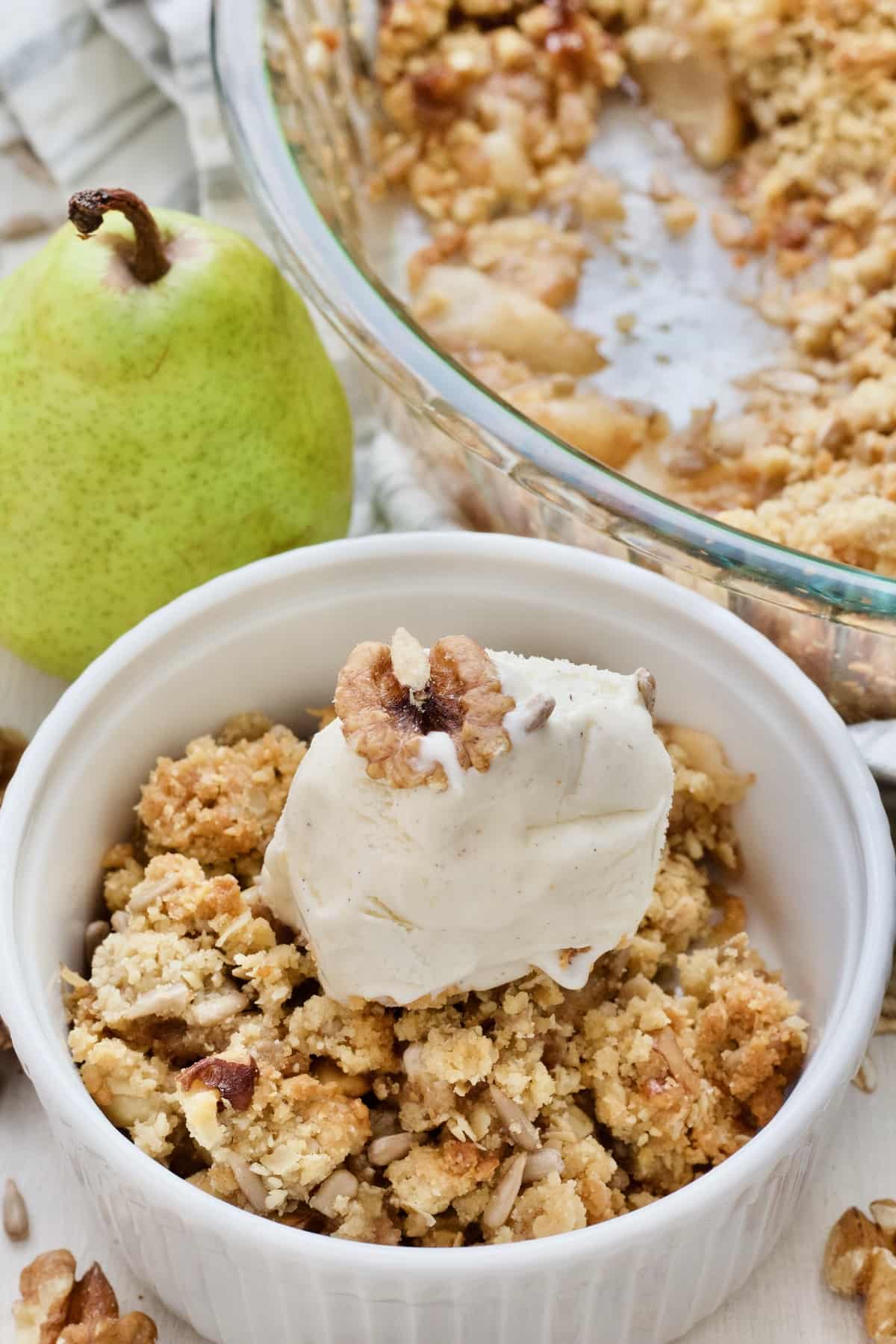 Close up of pear crumble portion in a bowl with ice cream.