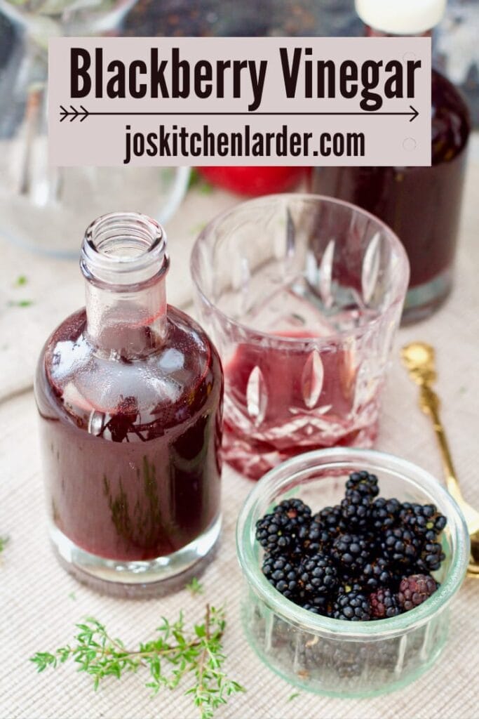 Bottles vinegar, tumbler and bowl with blackberries.