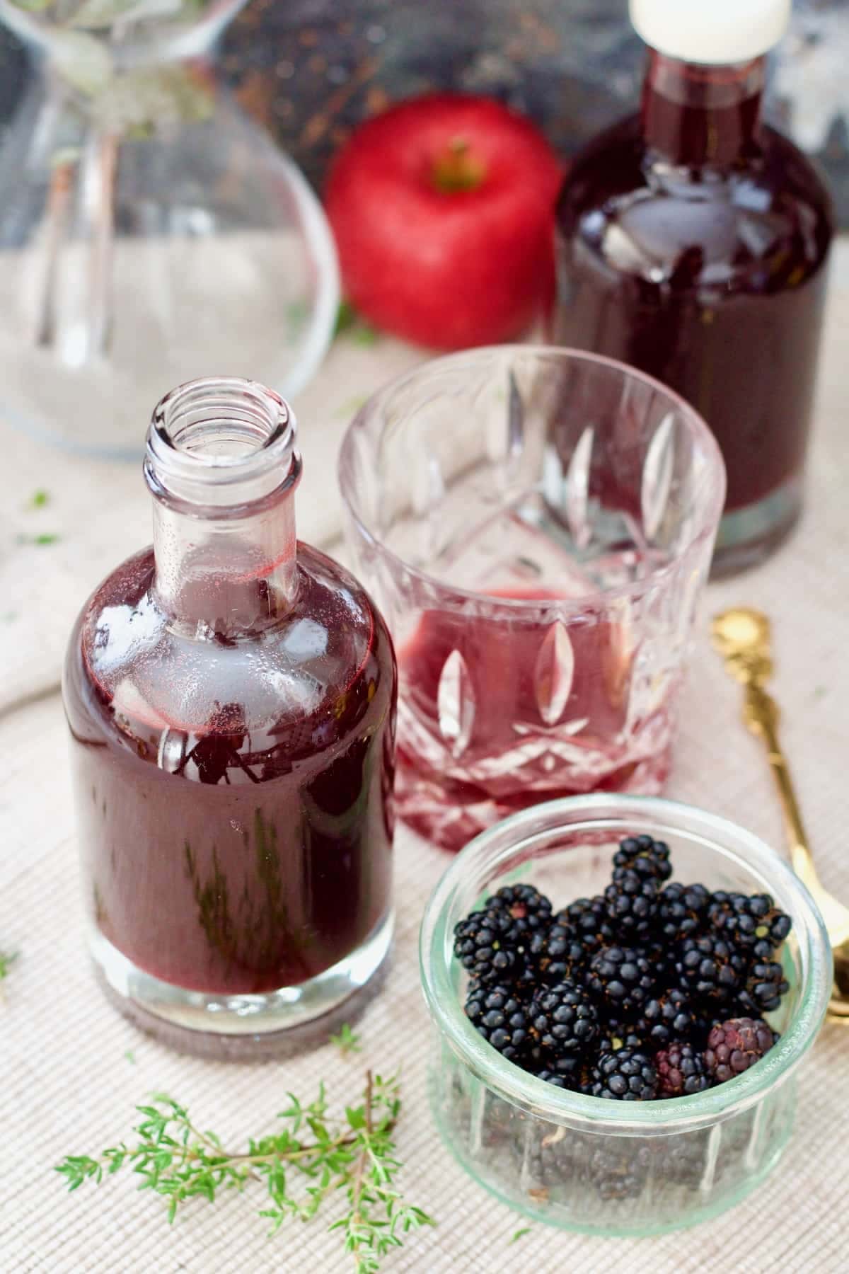 Bottle of blackberry vinegar, tumbler and bowl with blackberries.