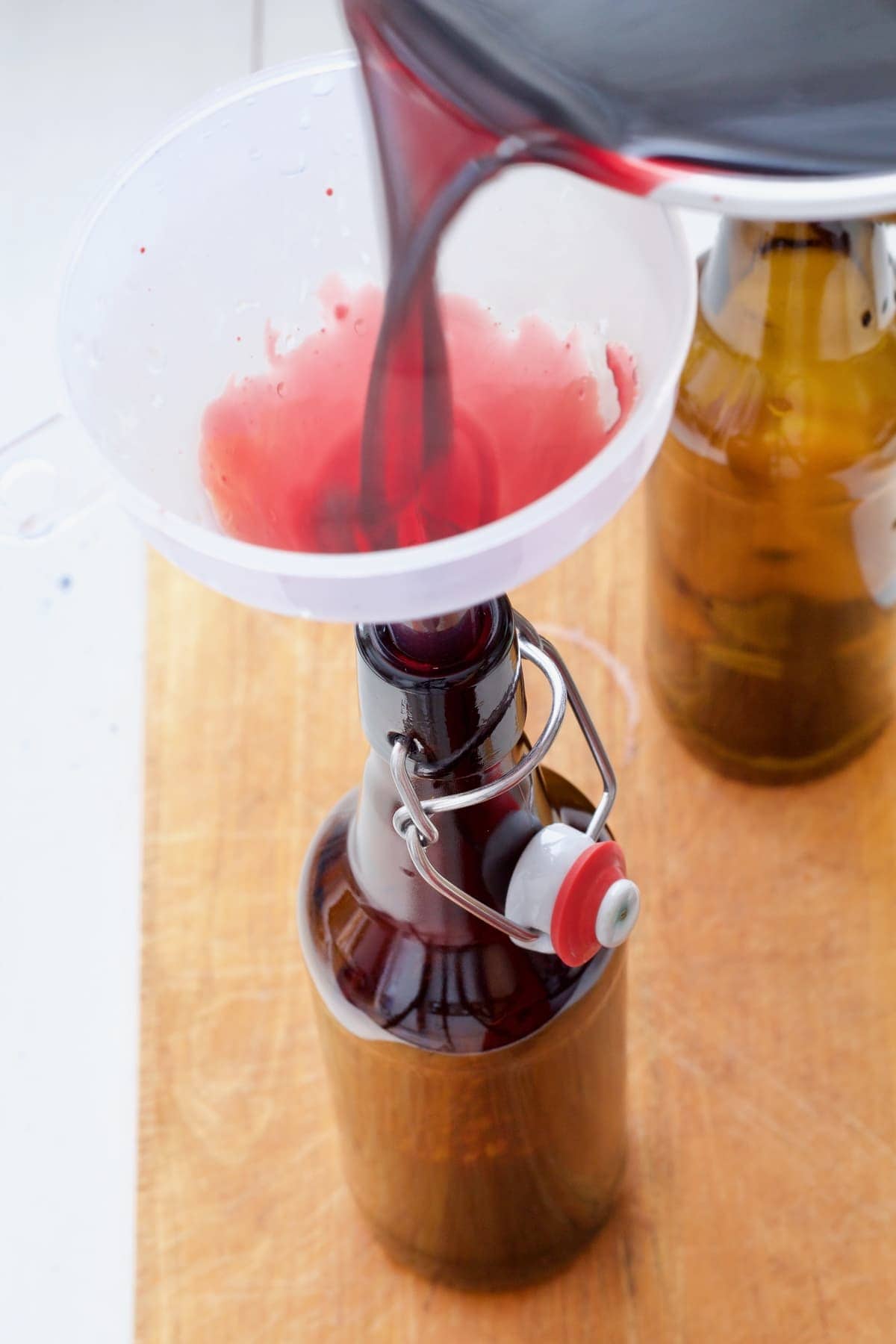 Pouring syrup into a bottle through a funnel.