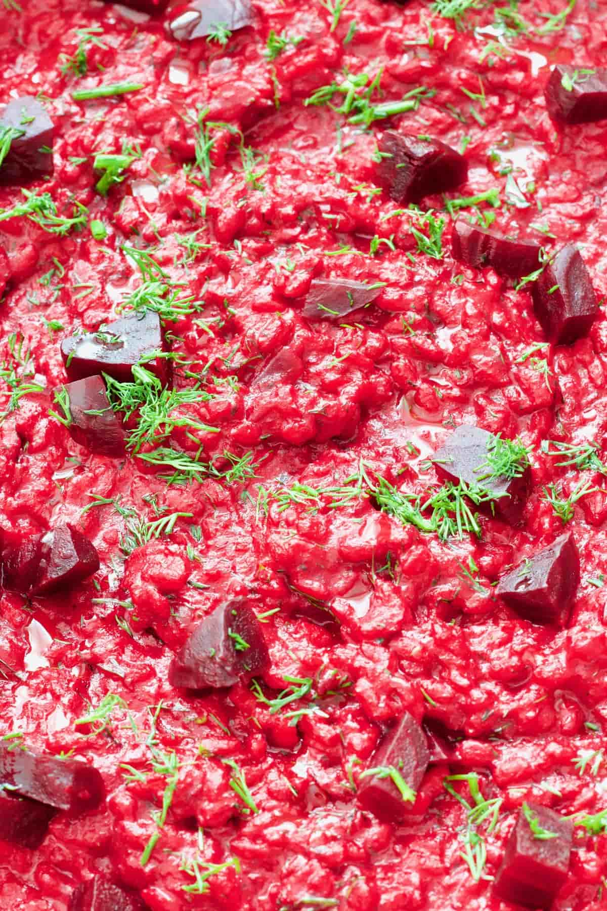Beetroot risotto with chunks of beetroot and fresh dill garnish.