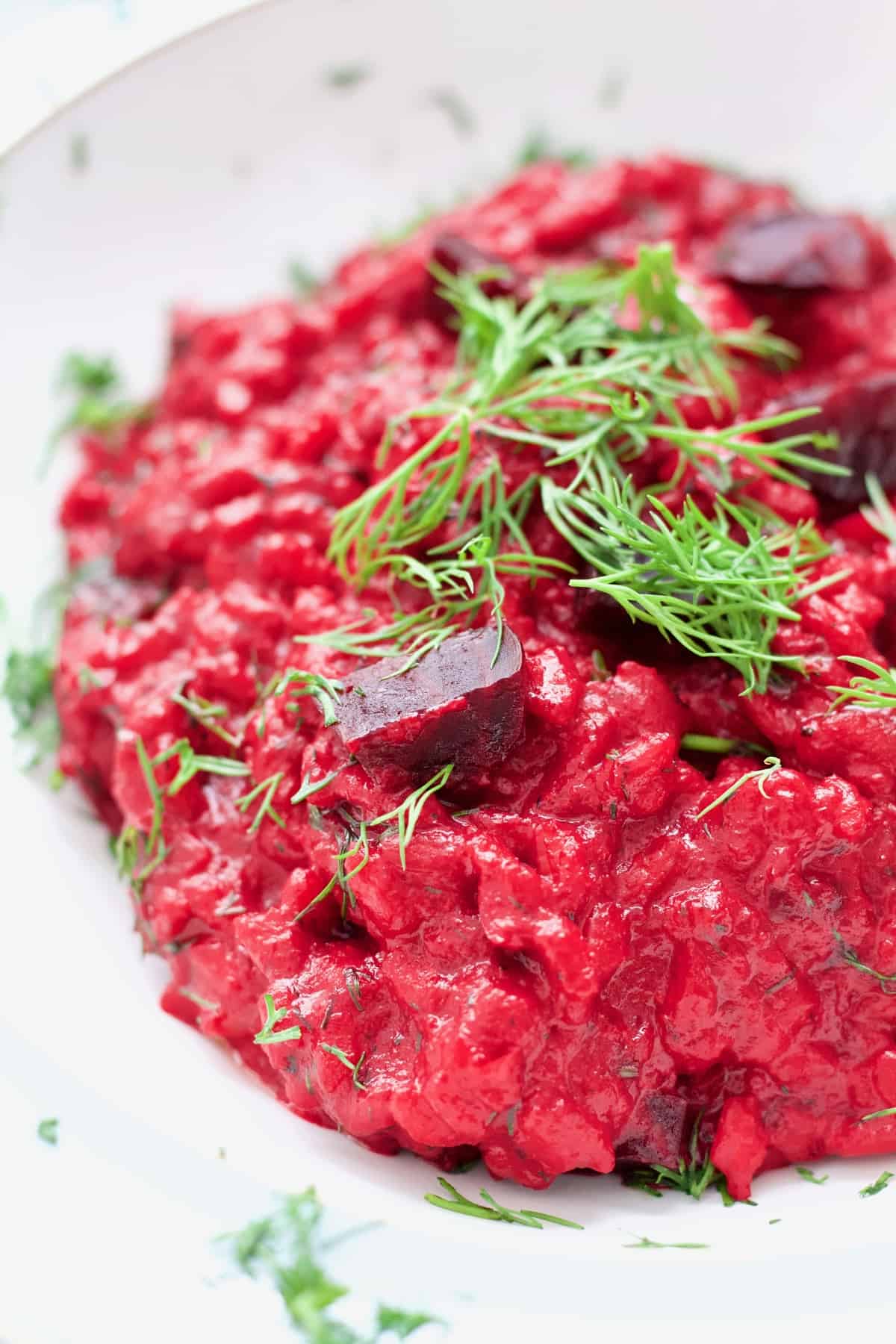 Close up of beetroot risotto portion with beetroot chunks and dill.