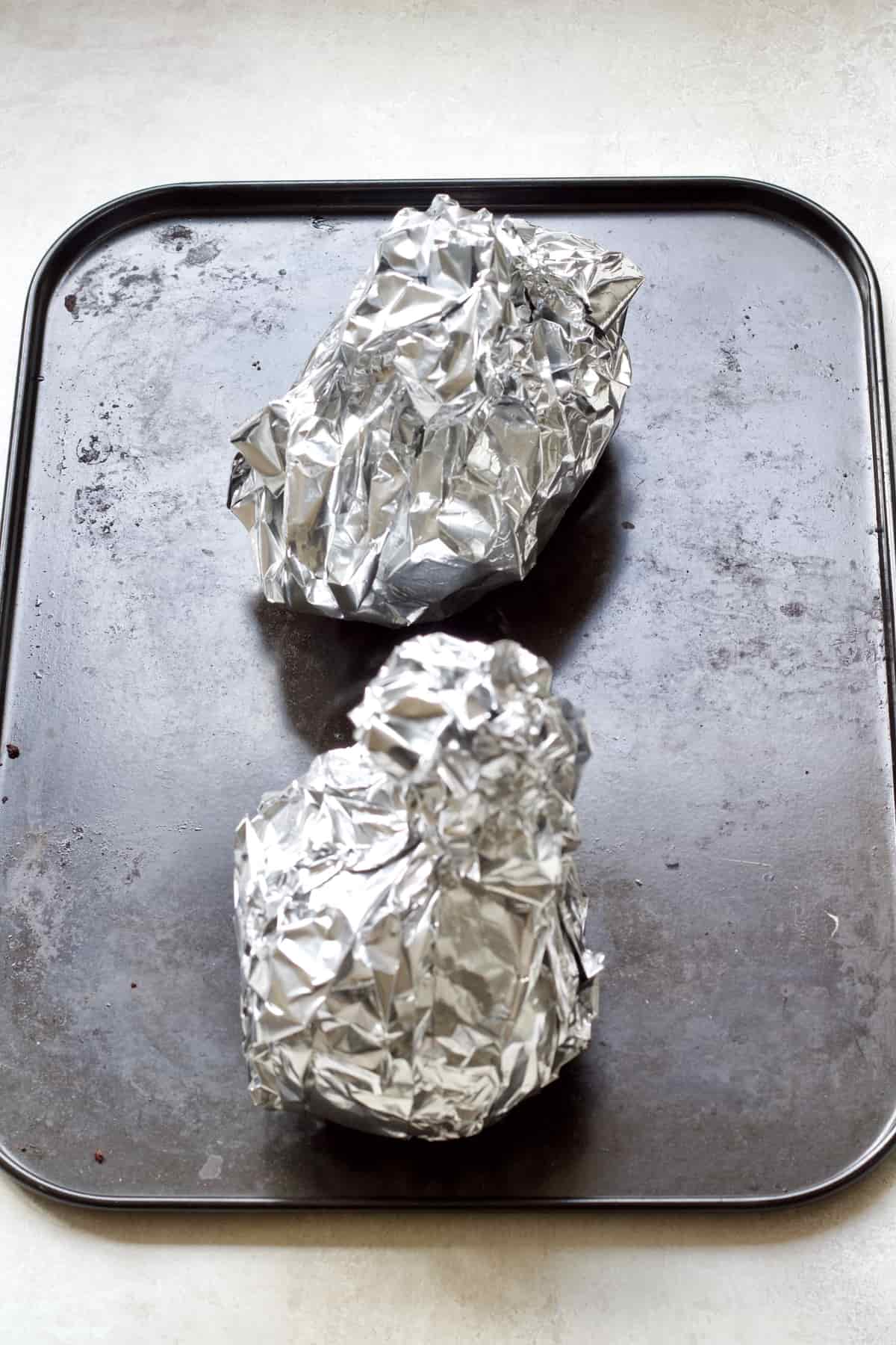 Beetroot in aluminium foil parcels on a tray.