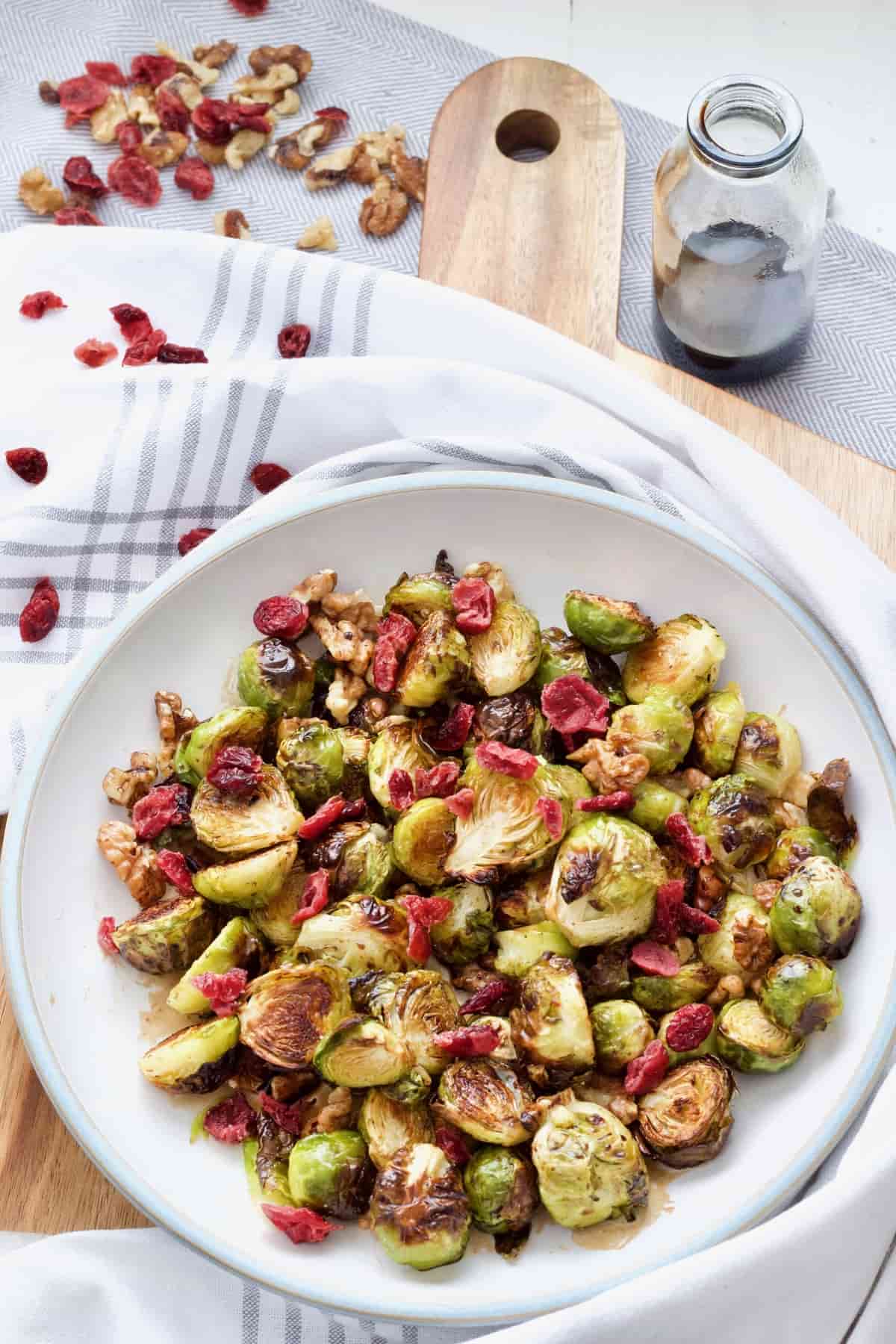 Roasted brussels sprouts with cranberries in a bowl on a board.
