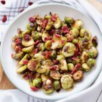 Bowl with roasted Brussels sprouts with balsamic vinegar and walnuts topped with cranberries.