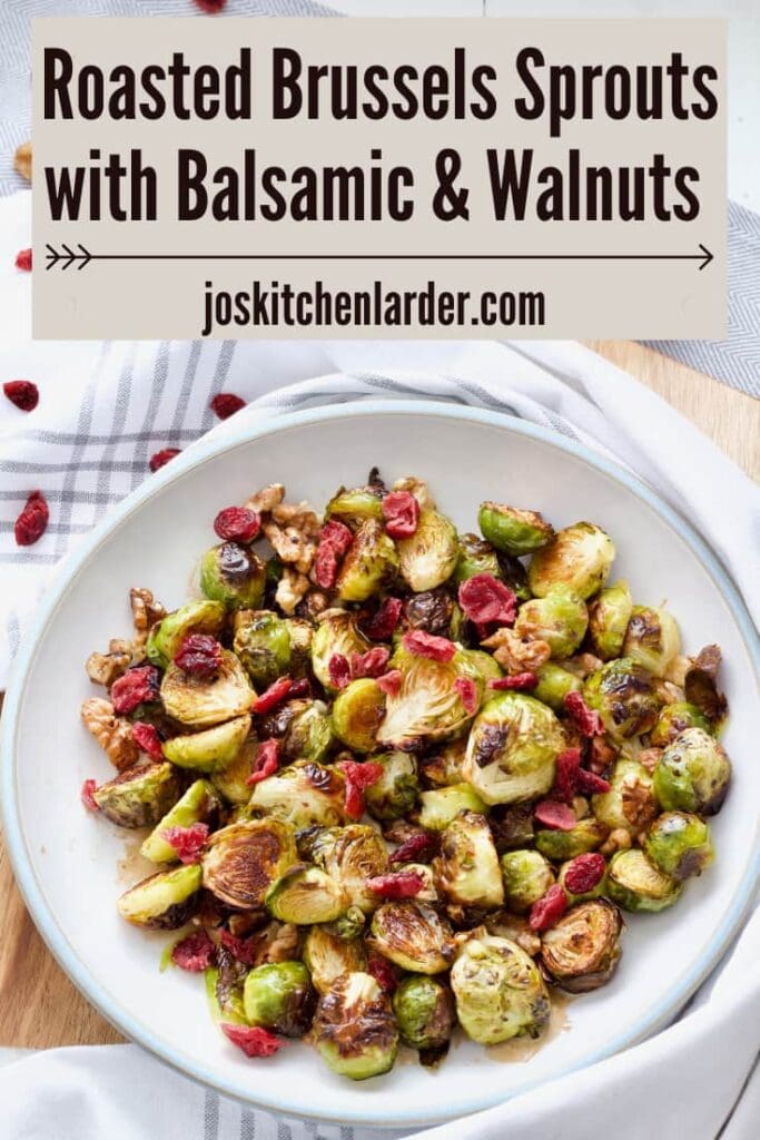 Roasted brussels sprouts with cranberries in a bowl on a board., image for Pinterest.