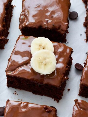 Square of vegan chocolate banana cake topped with banana slices.