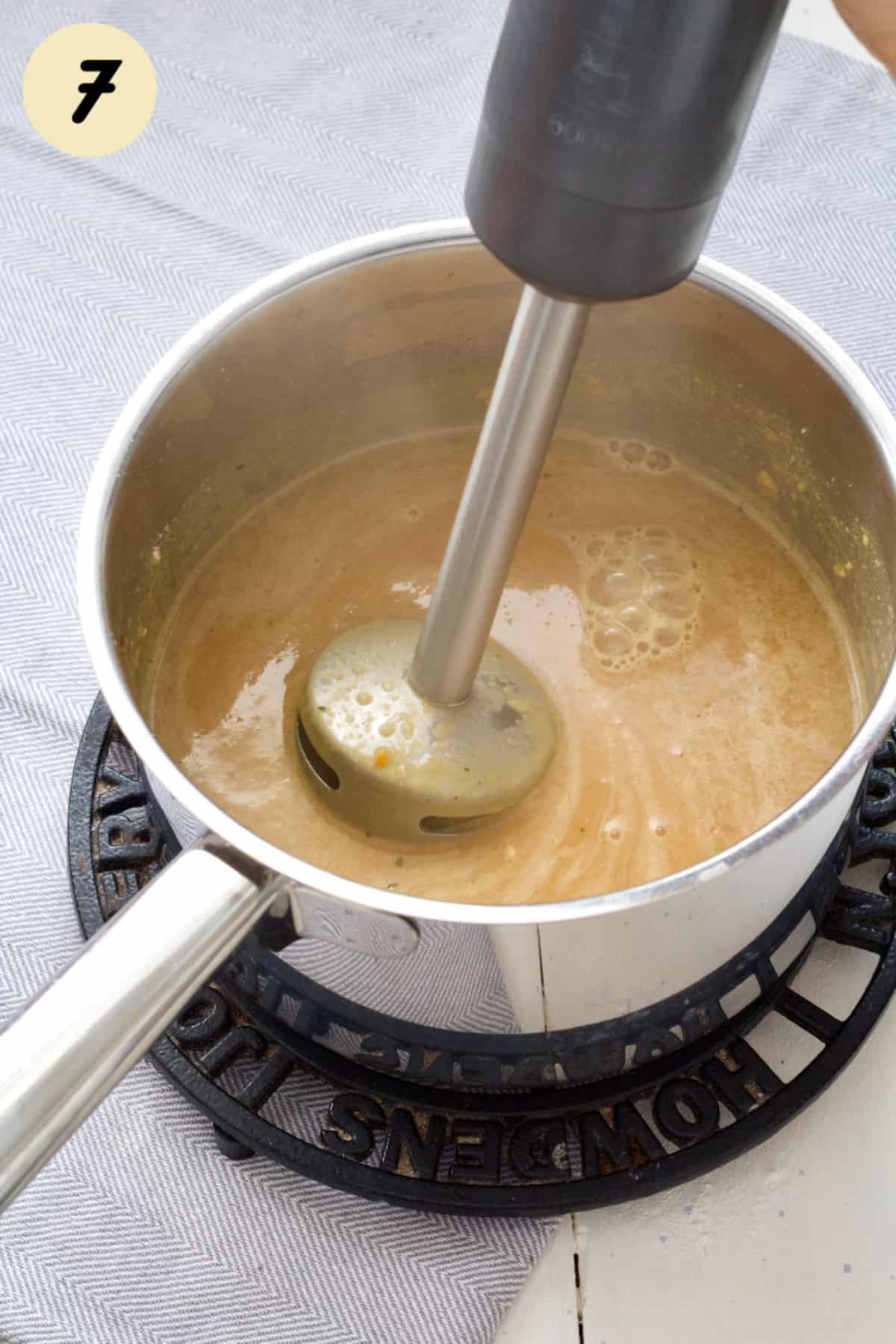 Vegan onion gravy being pureed with immersion blender.