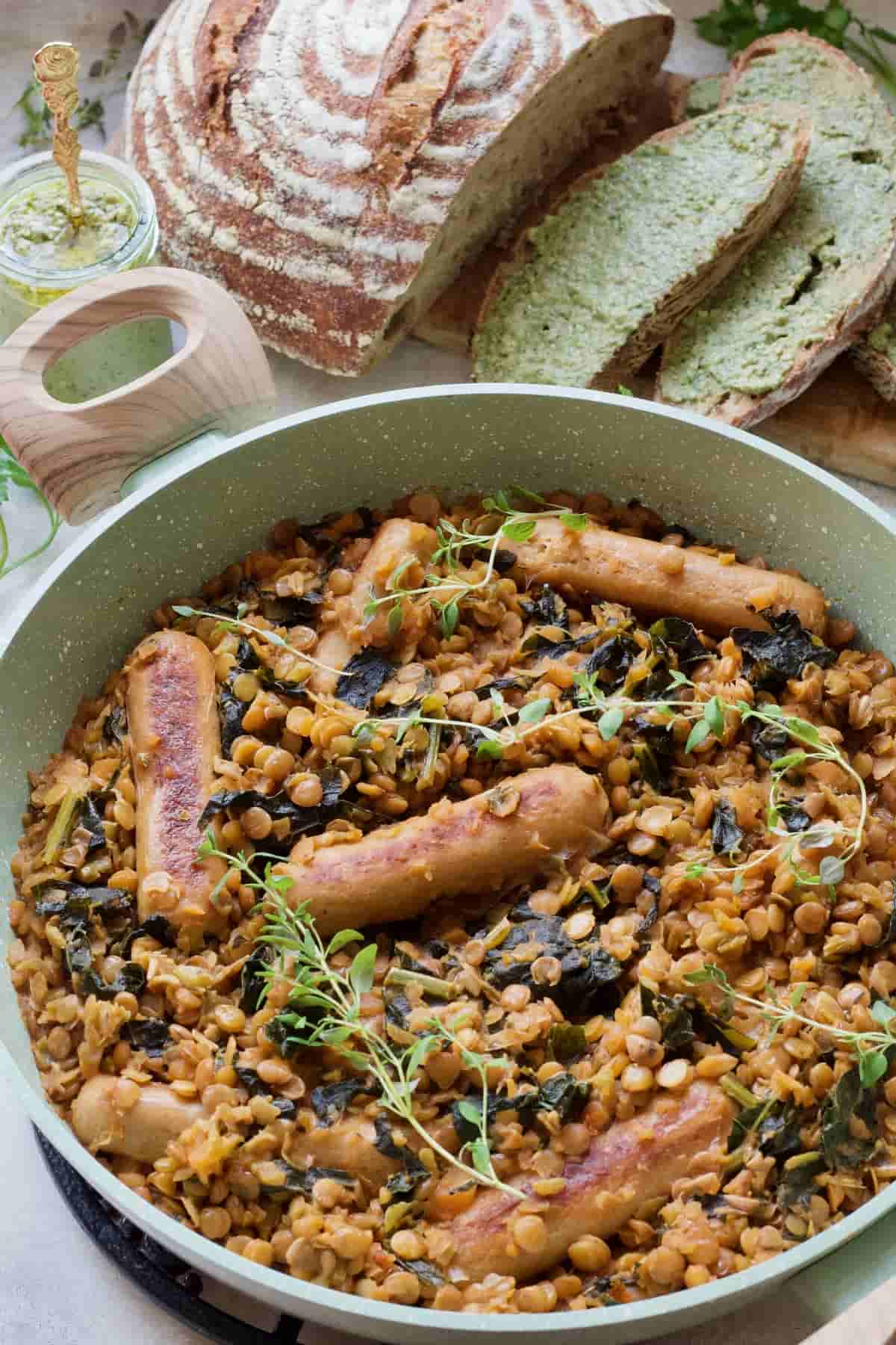 Pan with vegan sausage casserole, bread in the background.