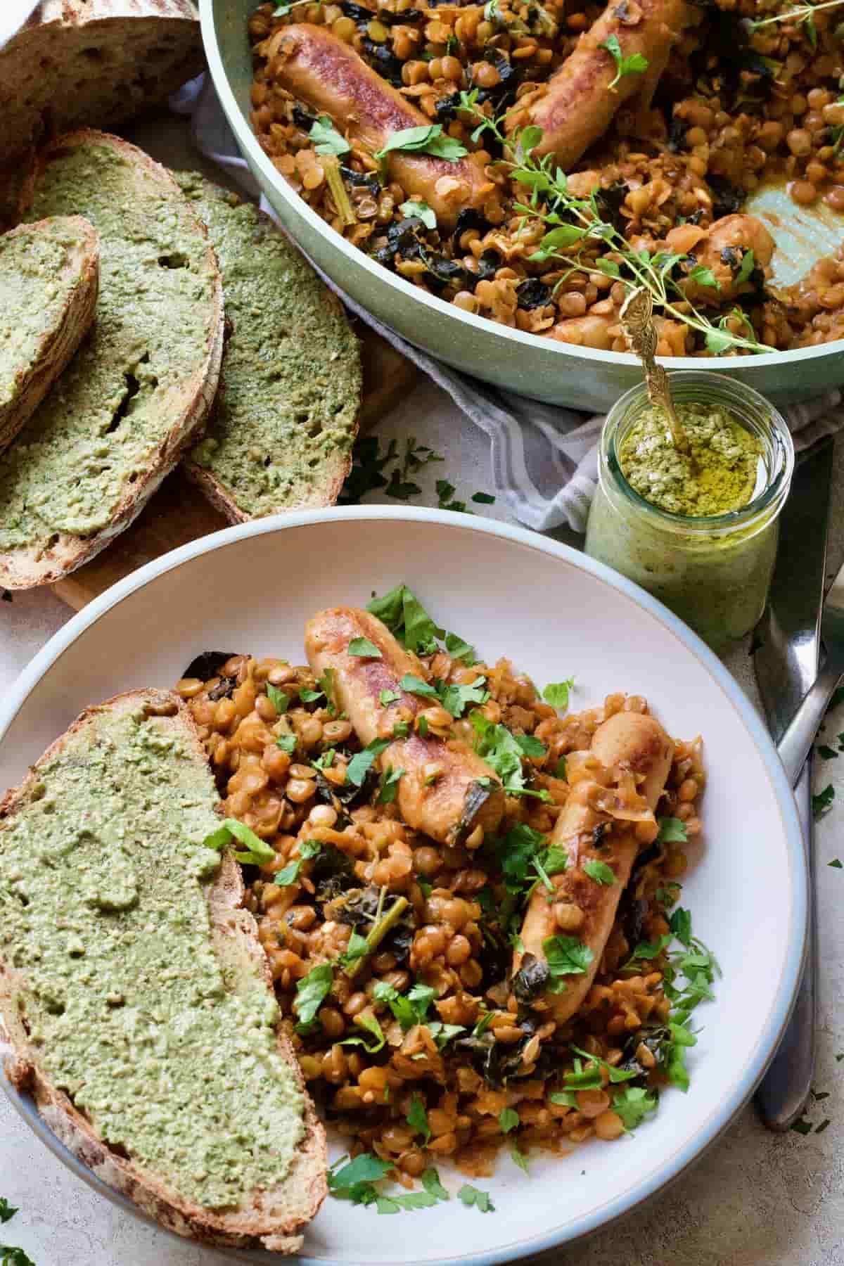 Plated up portion of vegan sausage casserole with a slice of bread with pesto.