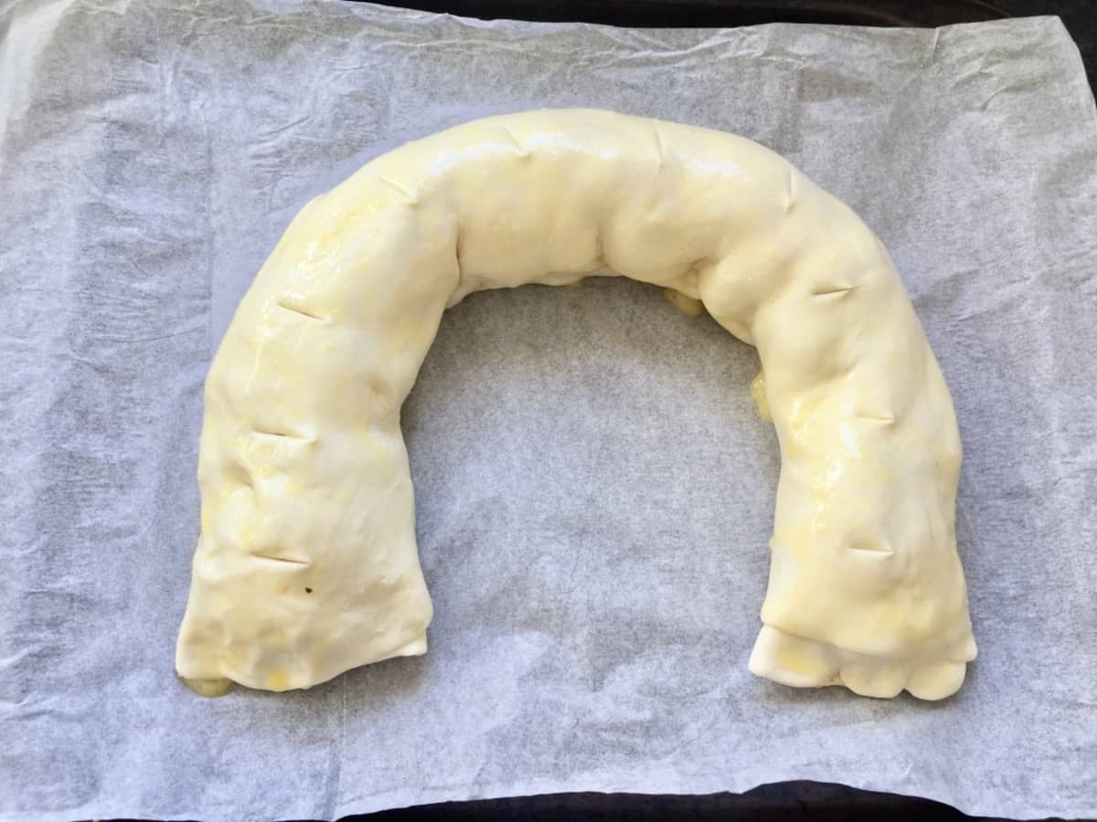 Vegan squash wellington shaped into crescent, scored and ready for baking.