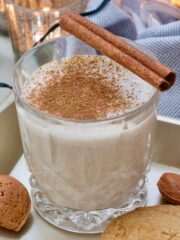 Tumbler with eggnog topped with cinnamon.