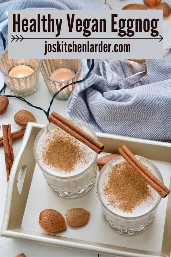 Two glasses with eggnog on a tray with tea lights in the background.