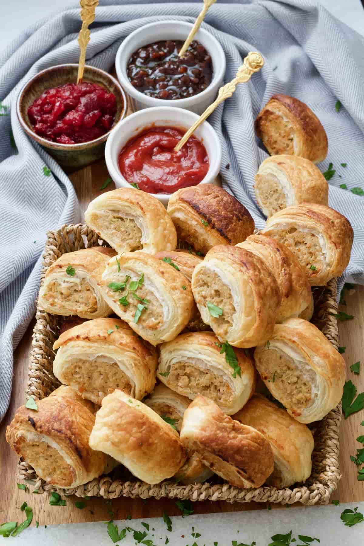 Vegan sausage rolls in the basket with sauces behind it.