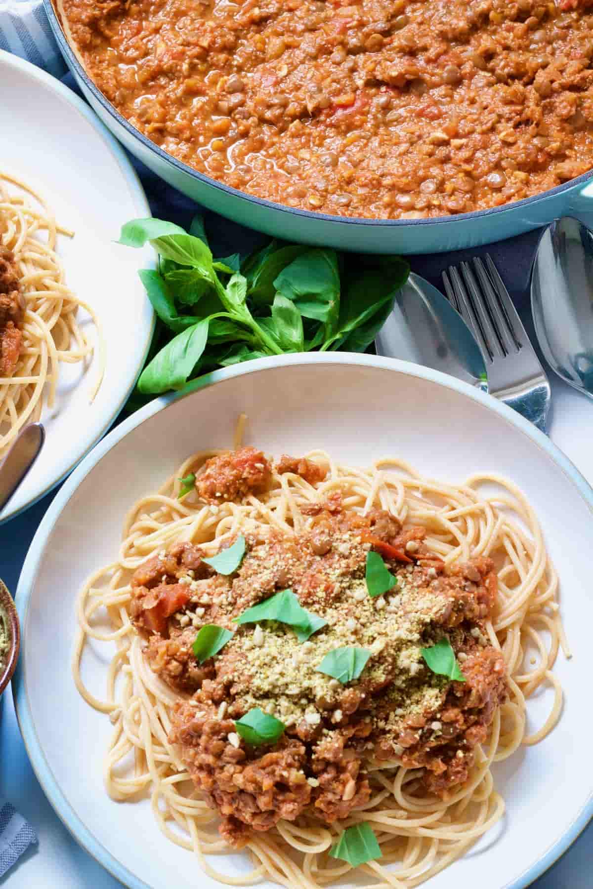 Lentil ragu over spaghetti with vegan parmesan and basil.