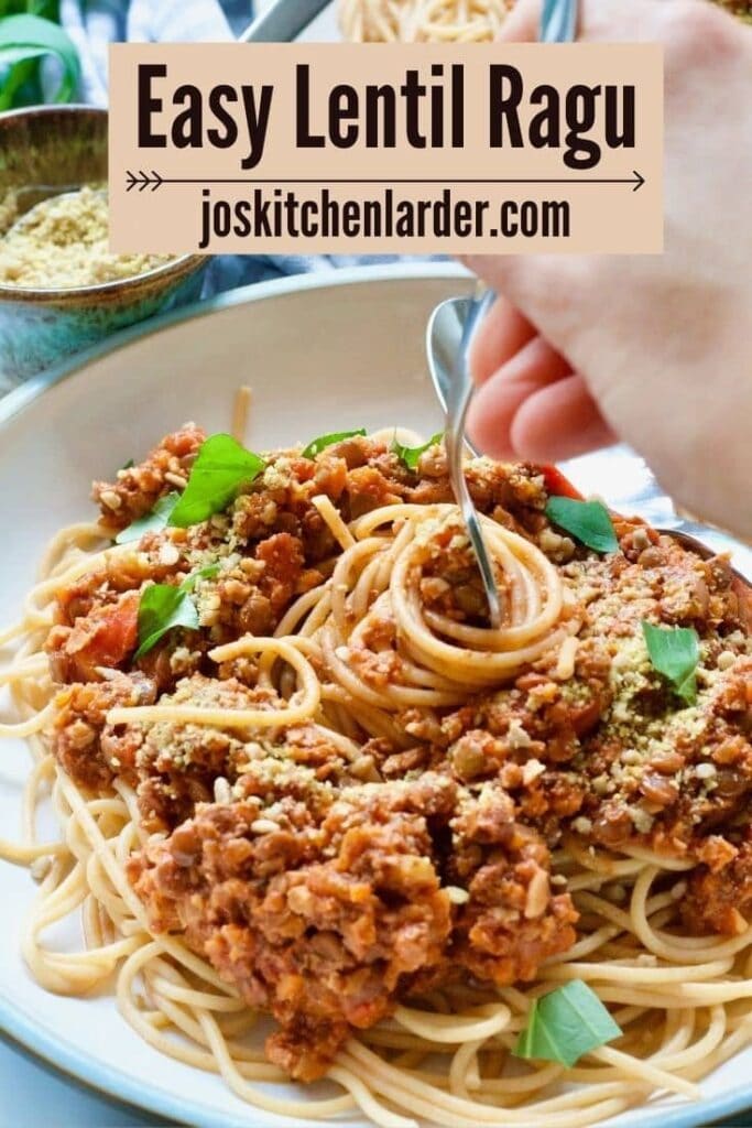 Hand picking forkful of vegan spaghetti bolognese.