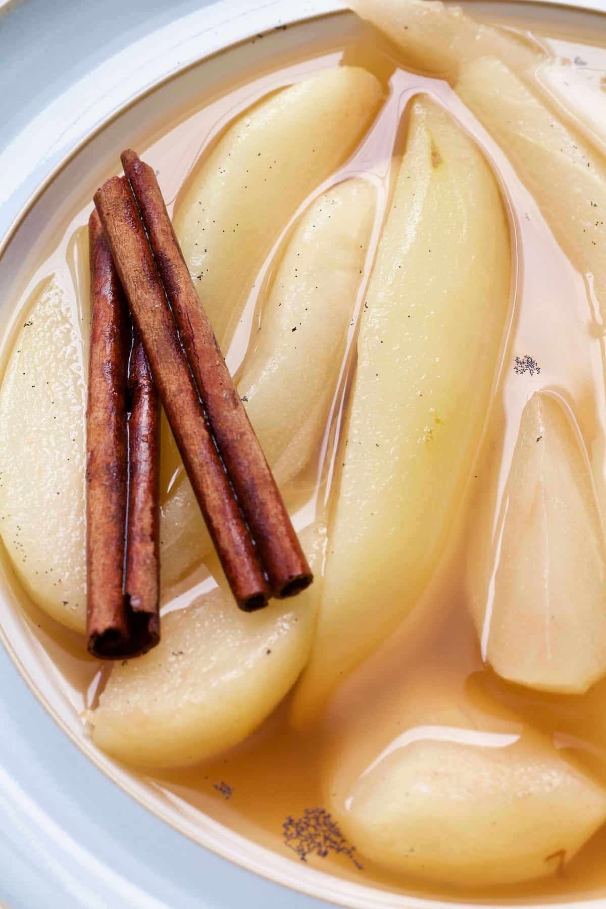 Stewed pears in a bowl with two cinnamon sticks.