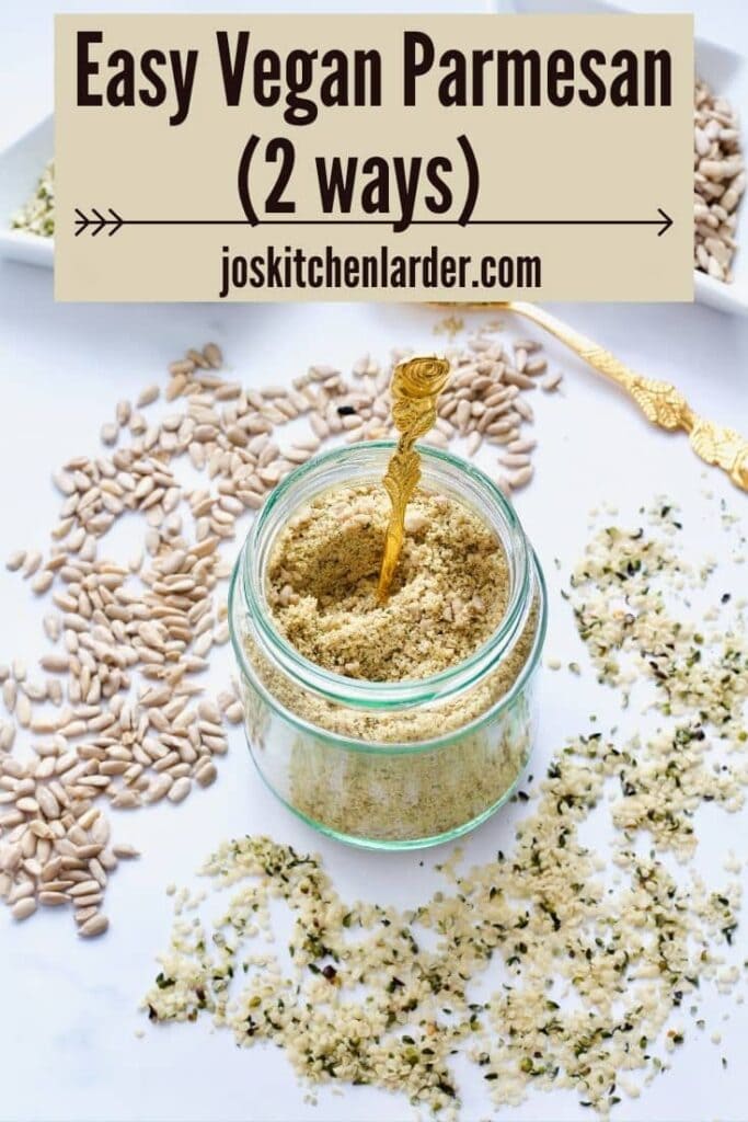Spoon in a jar with vegan parmesan, seeds scattered around.