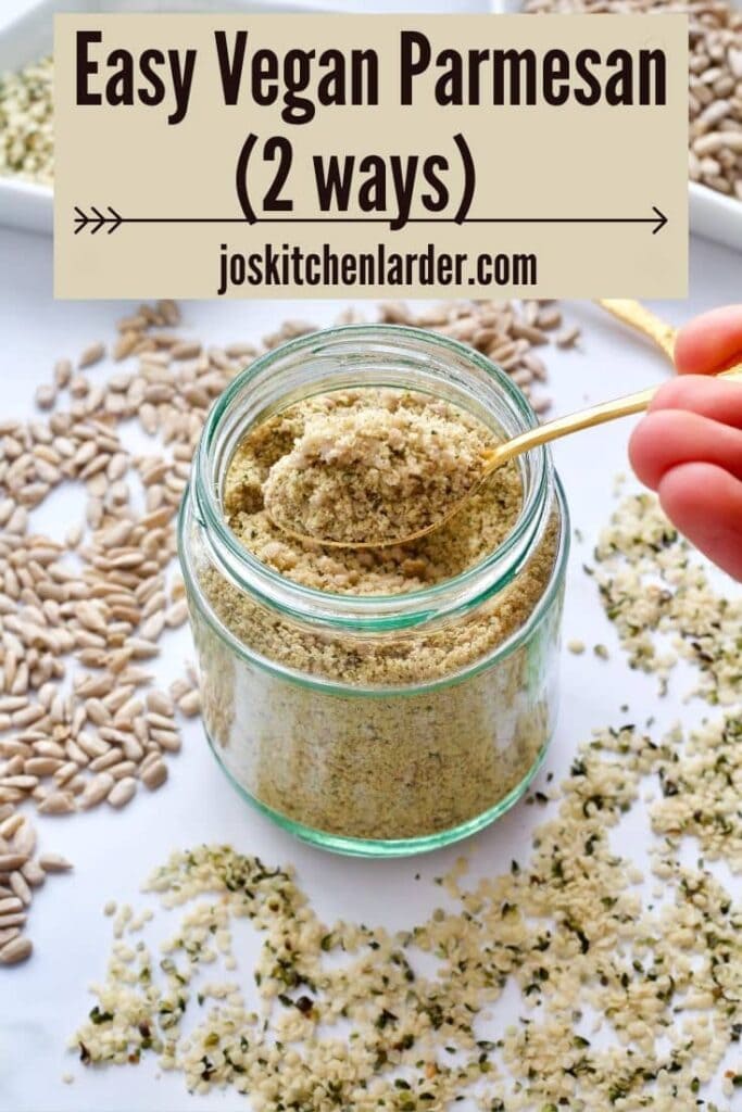Spoon with vegan parmesan over a jar, seeds scattered around.
