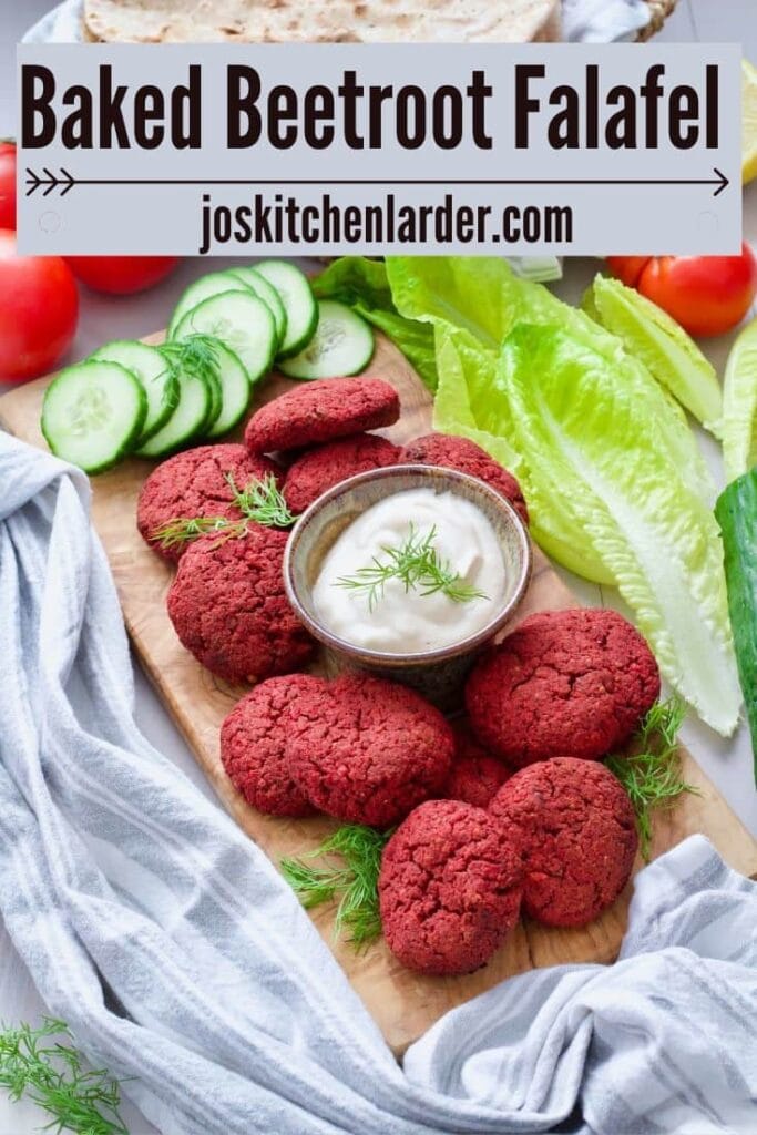 Beetroot falafel on a board with mayo dip in the middle, cucumber slices.