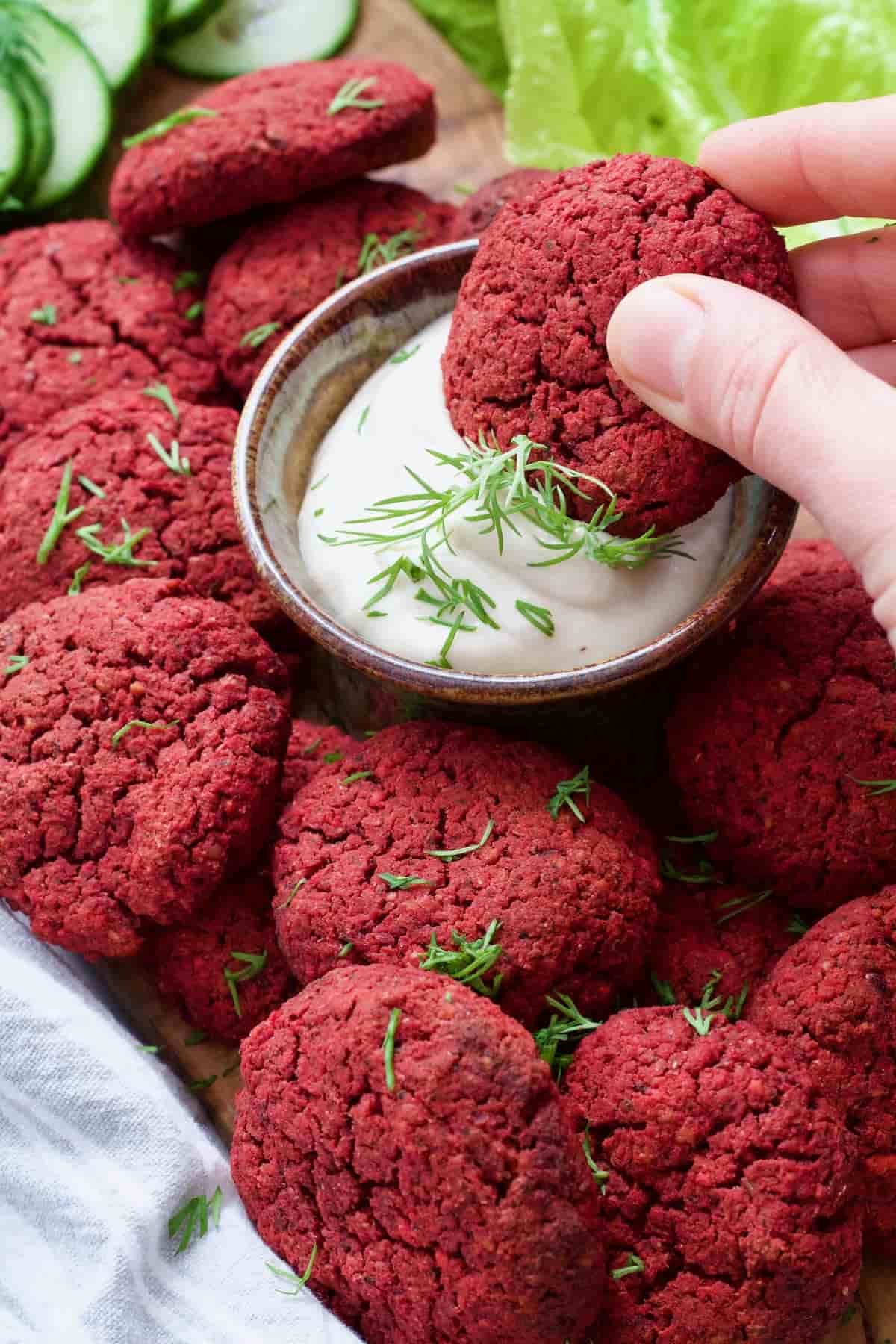 Beetroot falafel being dipped in mayo.