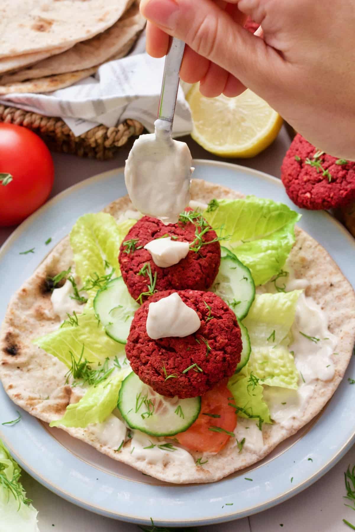Mayo being dolloped onto falafel in a flatbread.