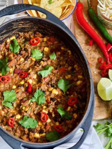 Large pot of vegan chilli topped with chilli slices and coriander.