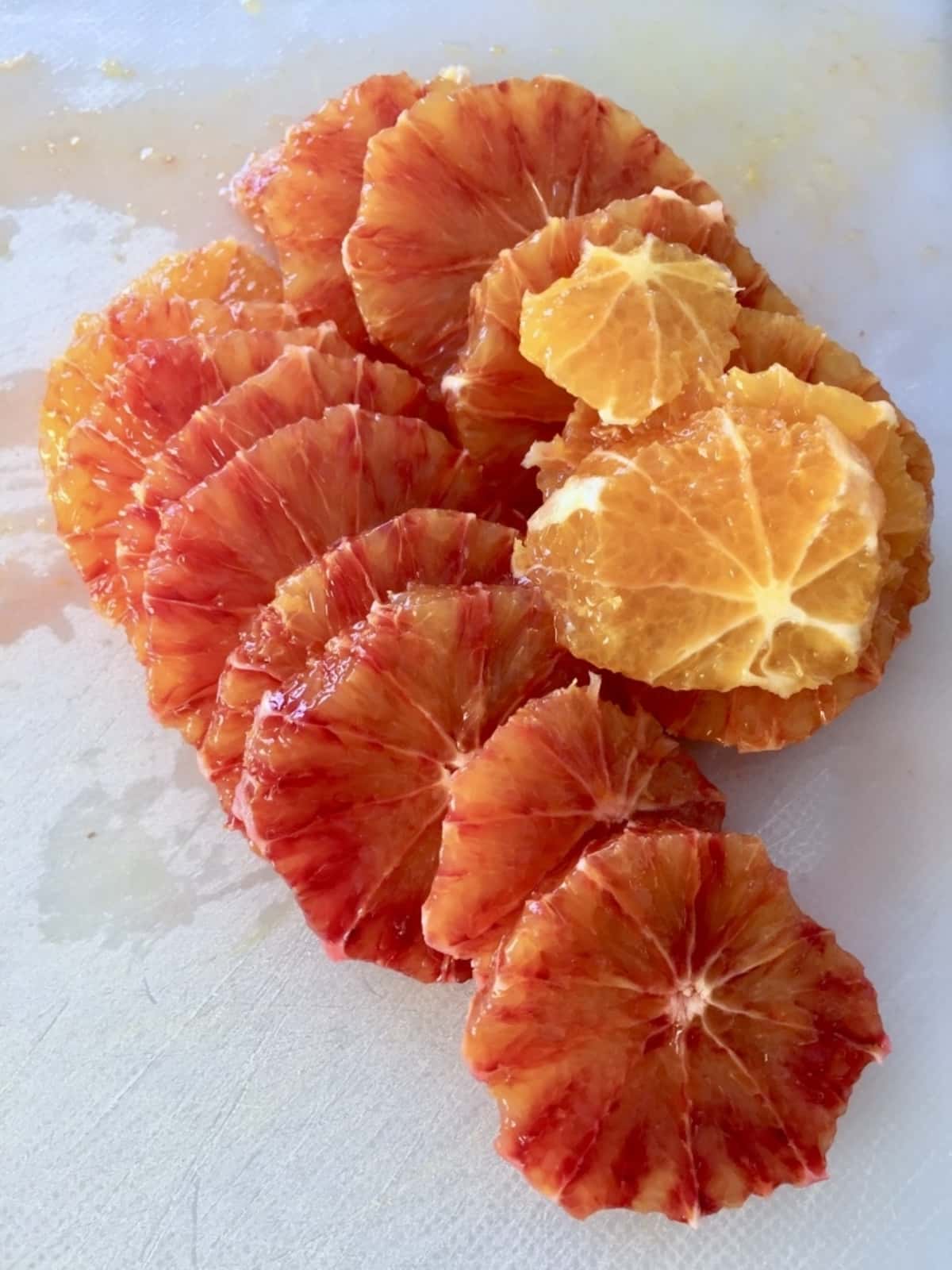 Slices of peeled blood oranges on a board.