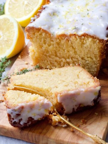 Slice of cake on a board with fork cutting through it.