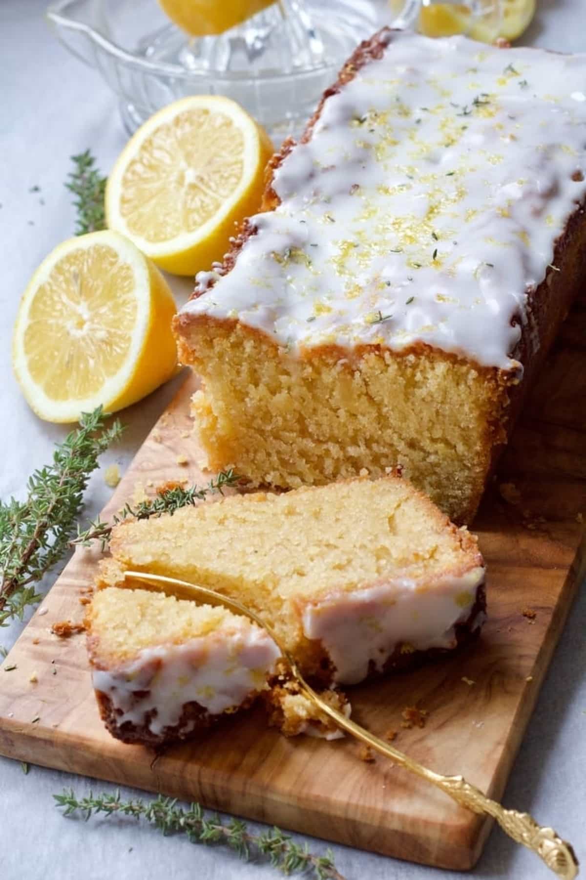 Vegan lemon drizzle cake on a board with slice being cut with a fork.