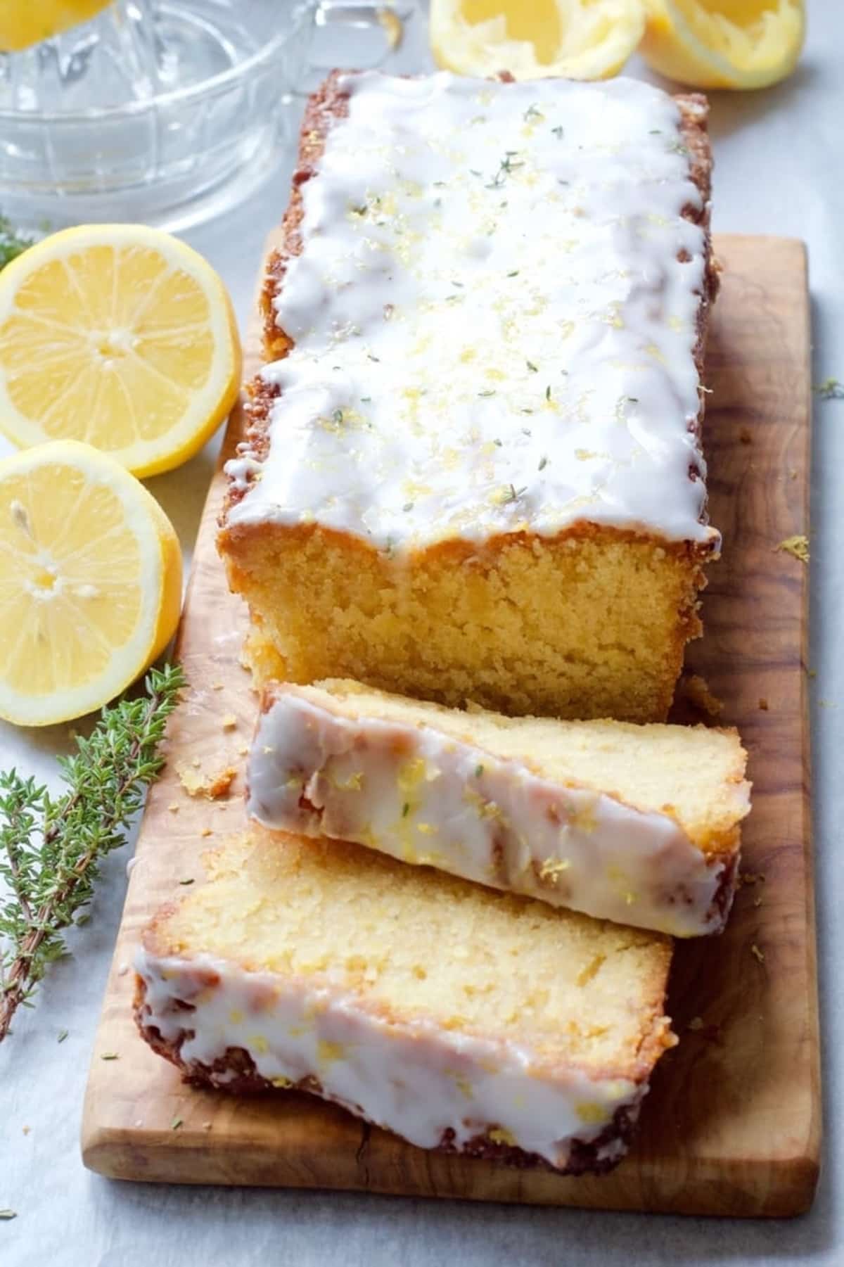 Iced loaf cake on a board with two slices cut.