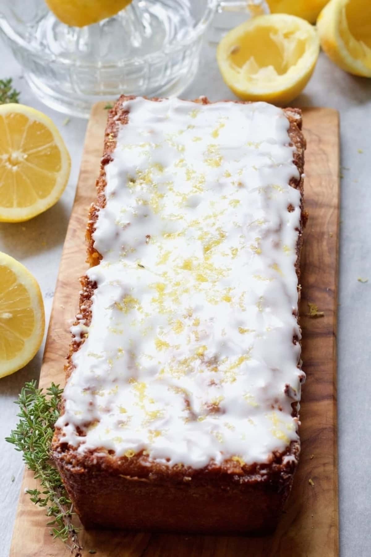 Iced vegan lemon drizzle cake on a wooden board.