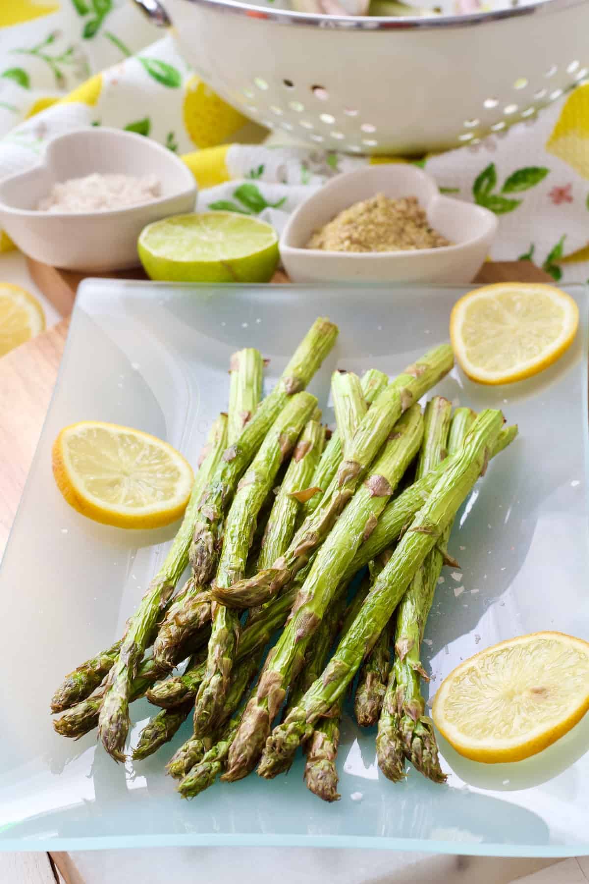 Air fried asparagus on a platter with lemon slices.