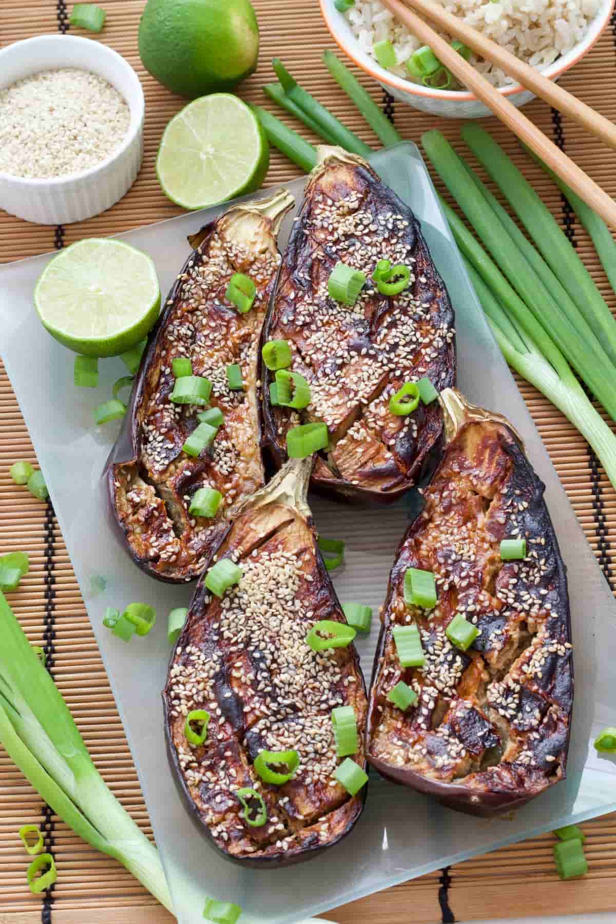 Plater with four miso-glazed aubergine halves topped with spring onion slices.