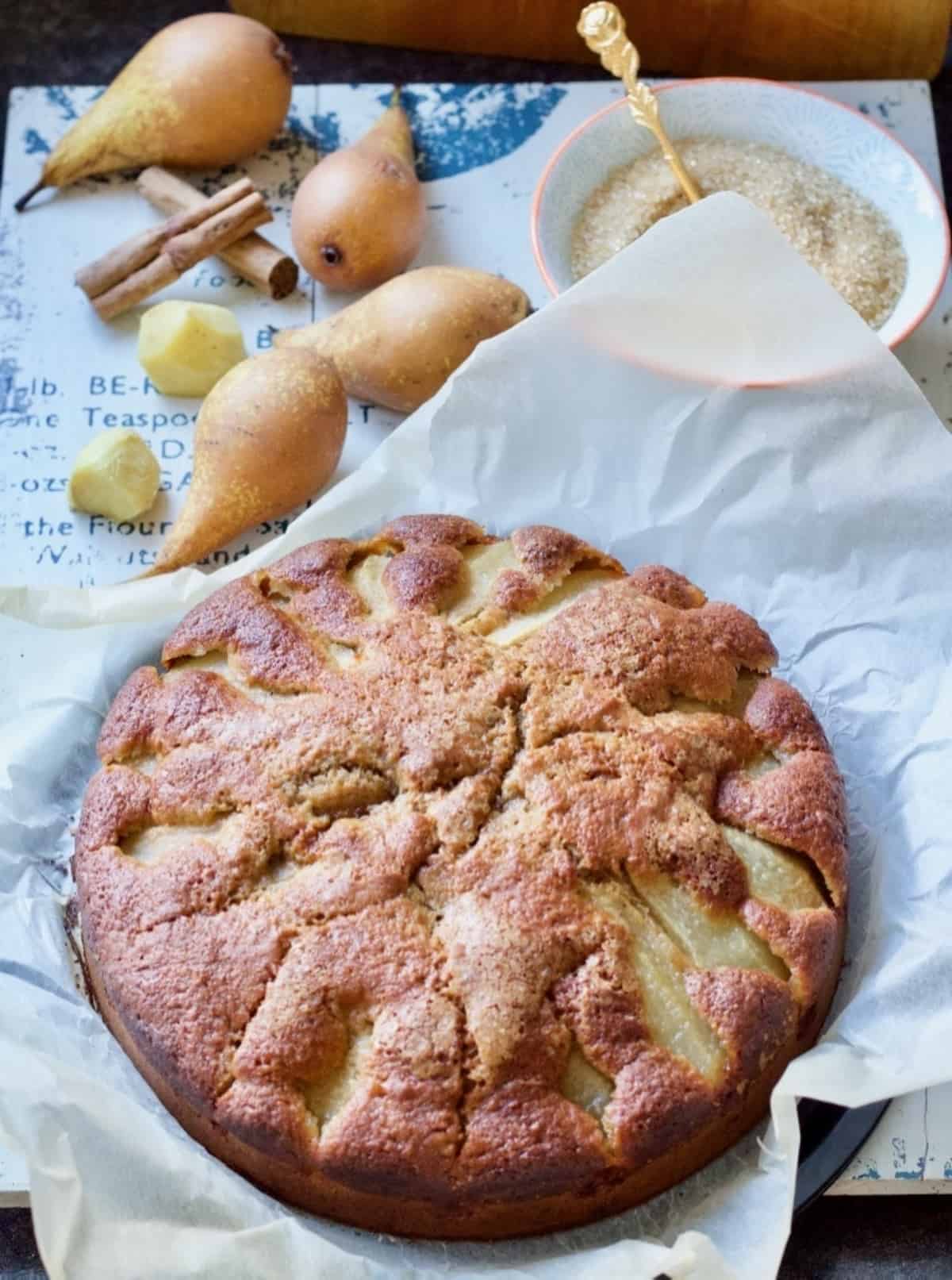 Pear and fresh ginger cake, pears, cinnamon , ginger and sugar behind it.