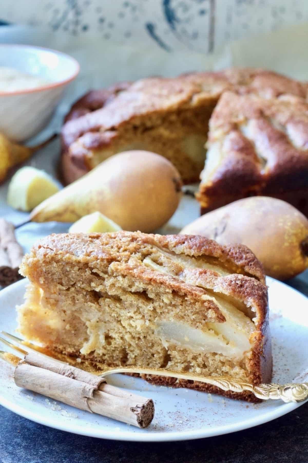 Slice of pear and fresh ginger cake on a plate with a fork.