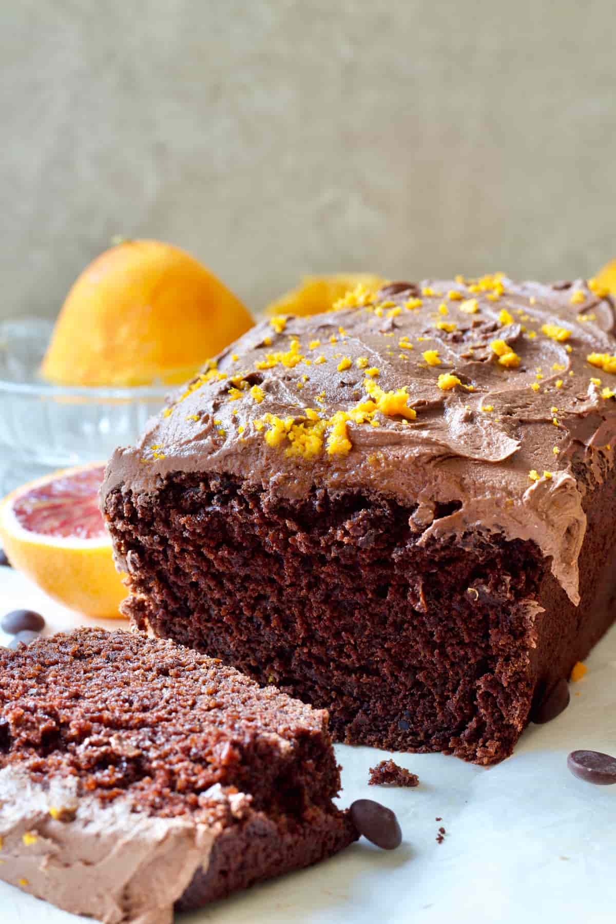 Vegan chocolate orange cake & slice with oranges in the background.