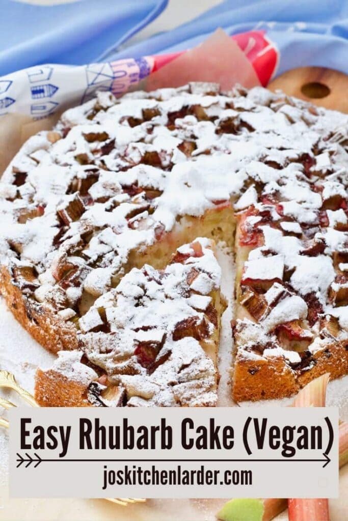 Easy rhubarb cake with a slice cut, dessert forks and pieces of raw rhubarb.