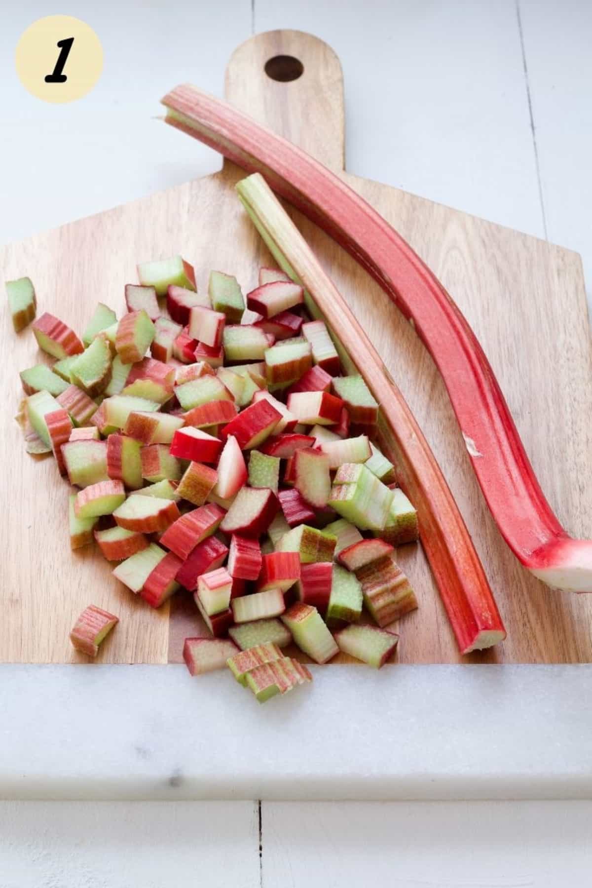 Raw rhubarb on a cutting board, partially chopped into chunks.
