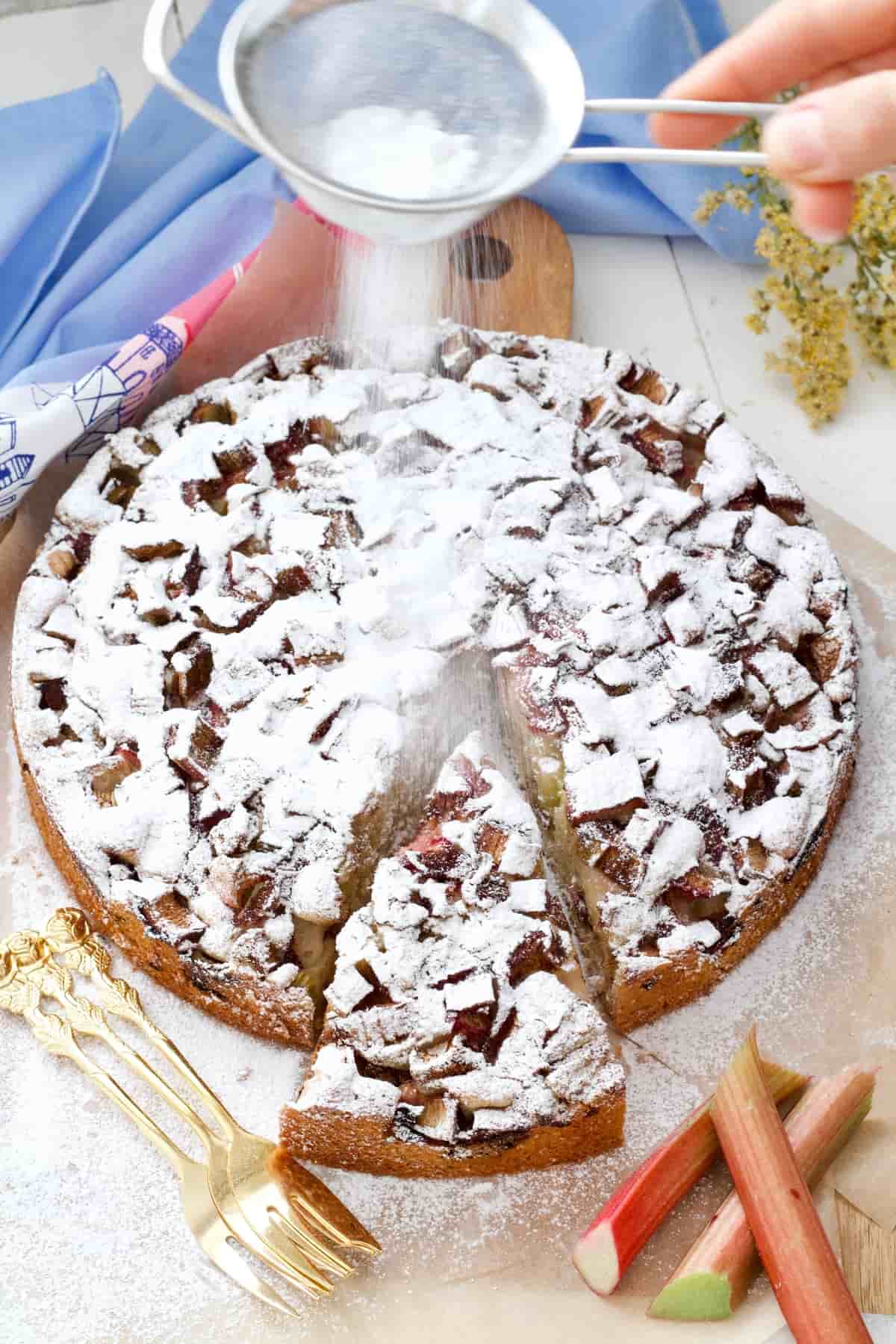 Icing sugar being dusted over the rhubarb cake.