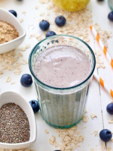 Close up of glass with oat milk smoothie and bowl with chia seeds.