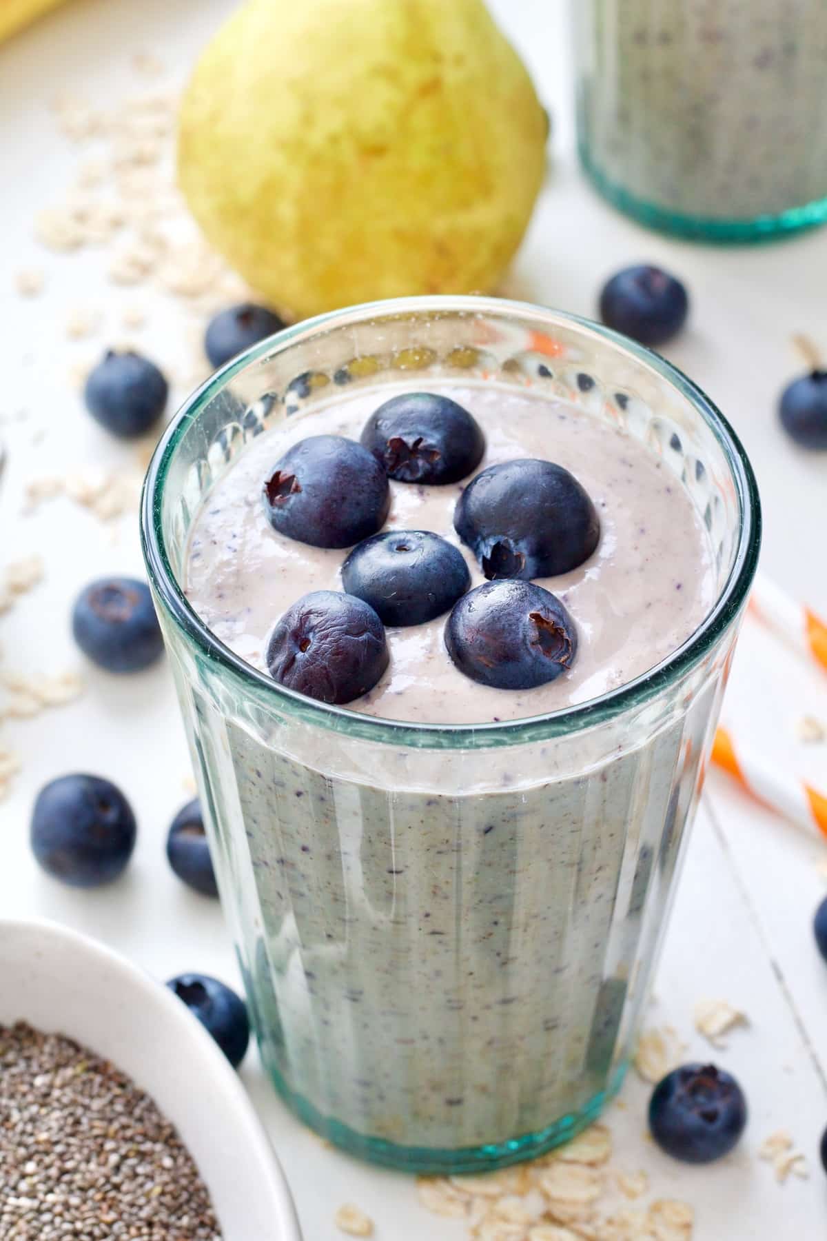 Glass filled with smoothie with fresh blueberries on top.