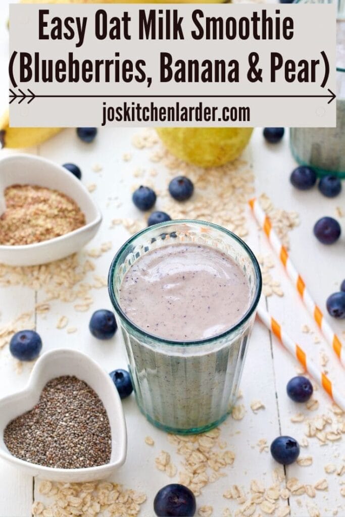 Glass with oat milk smoothies with oats & blueberries scattered around it.