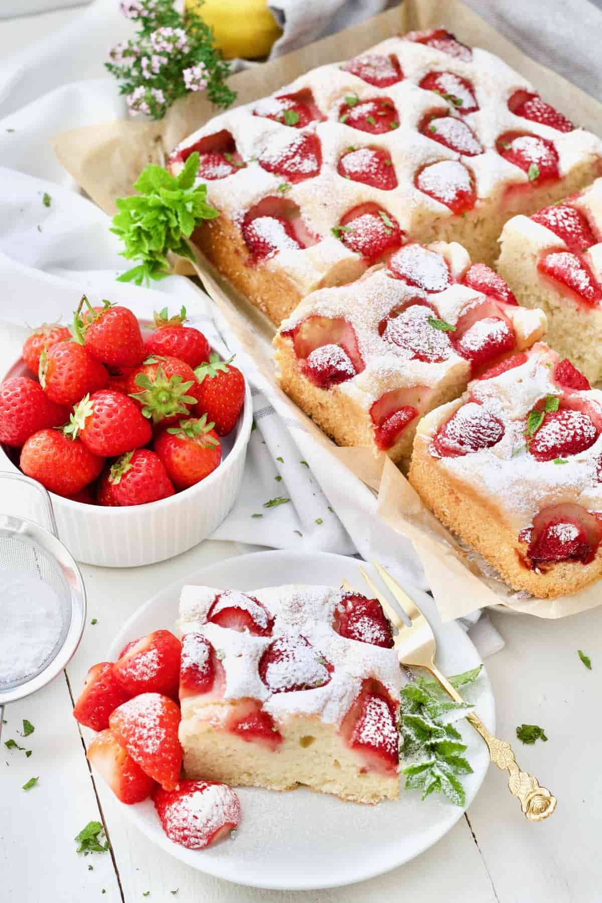 Fresh strawberry yogurt cake, slice on a plate and bowl with strawberries.