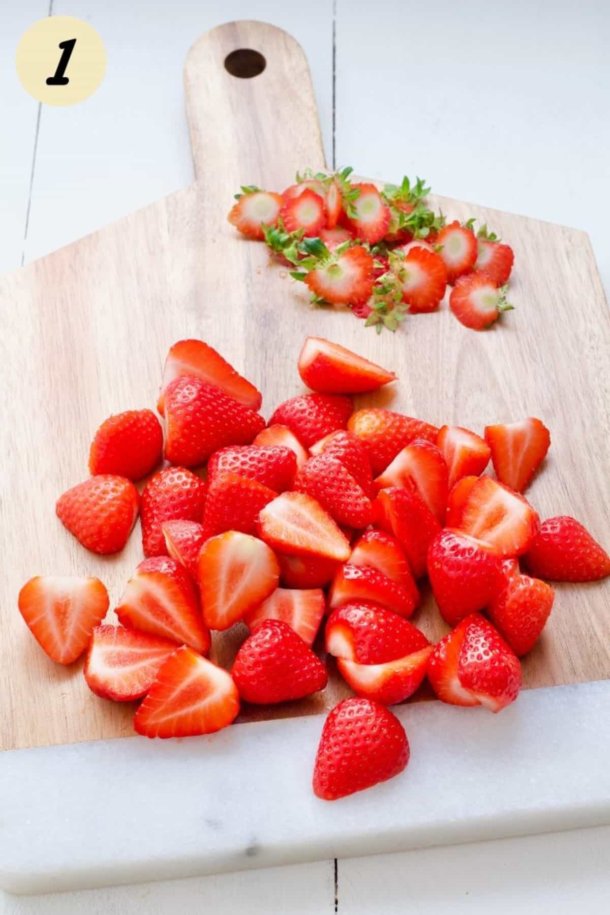 Hulled and halved strawberries on a board.