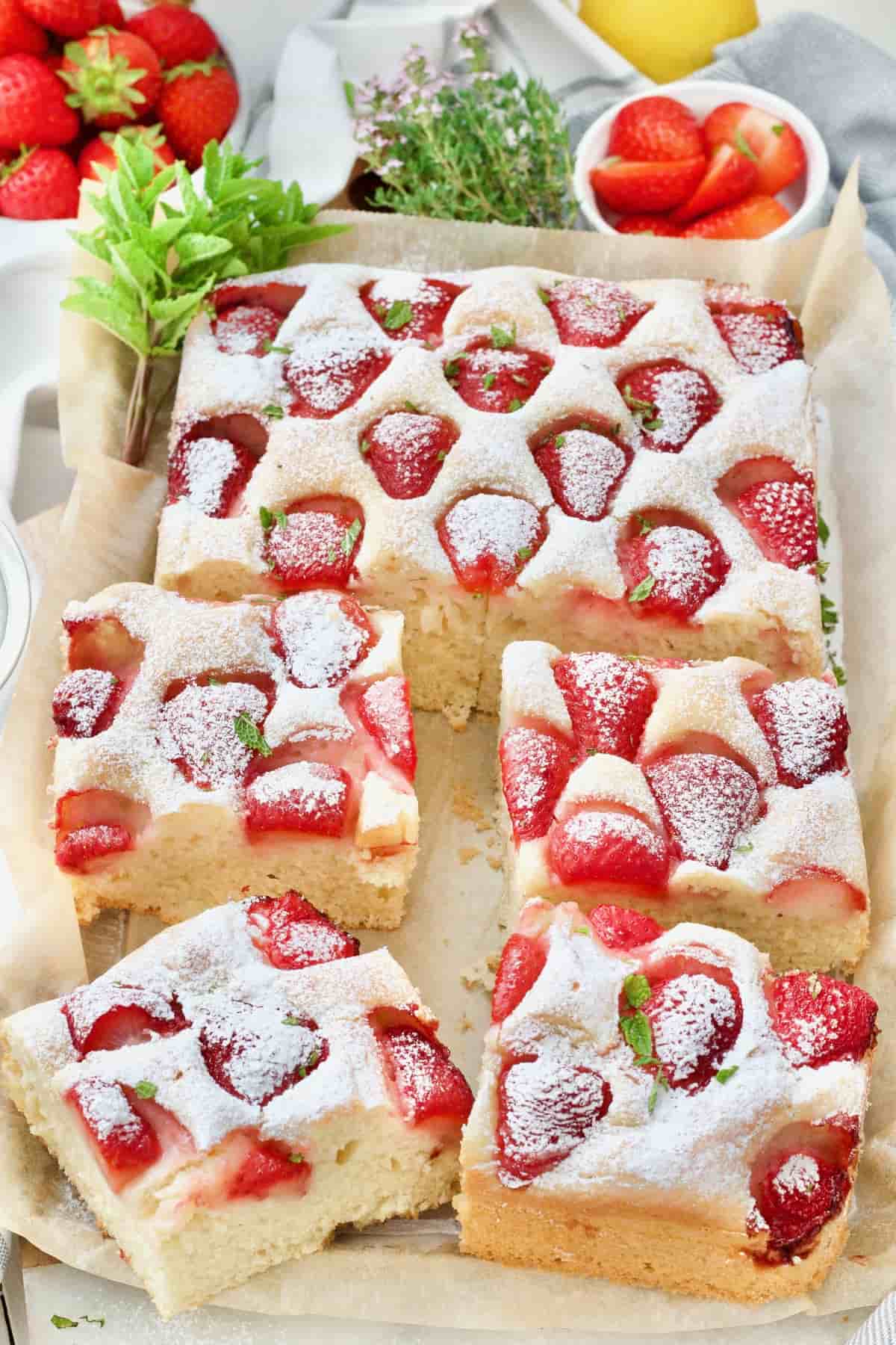 Strawberry traybake with four large portions cut.