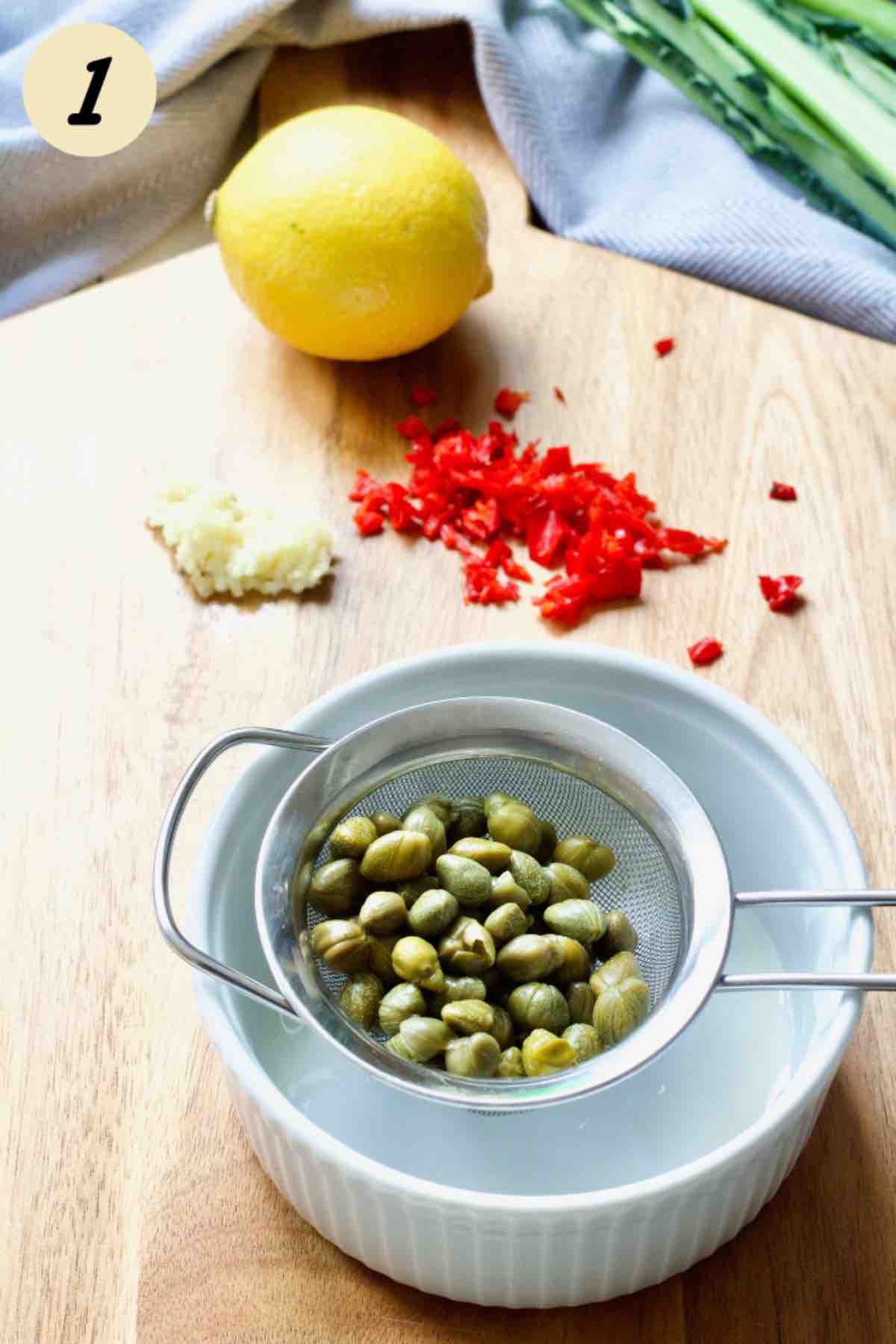 Draining capers in a sieve over a bowl.