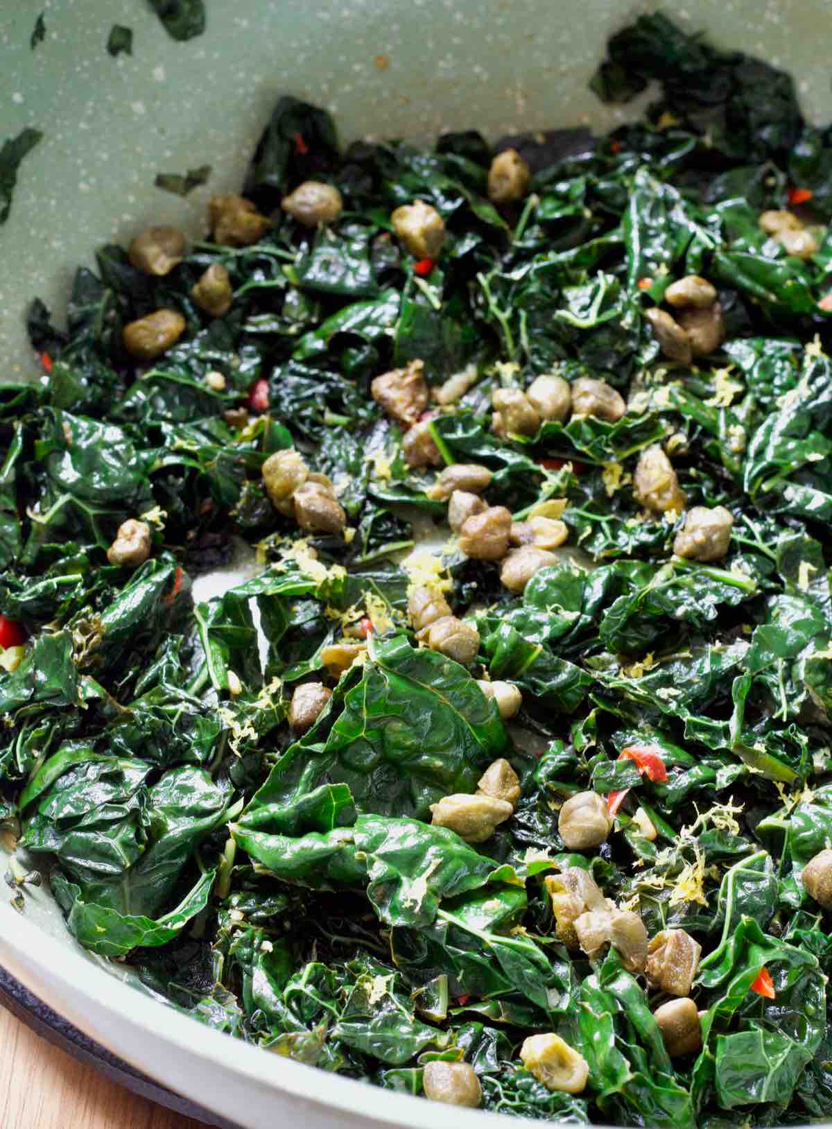 Frying pan with finished cavolo nero with chilli and garlic and some visible lemon zest.