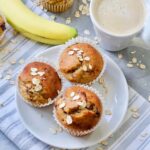 Close up of three banana muffins on a plate, coffee and a banana.