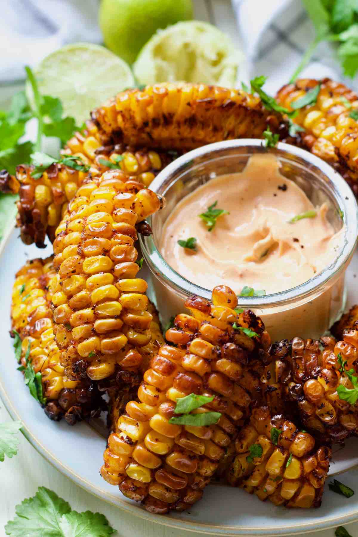 Corn giblets arranged on a plate around bowl with a dip.